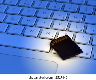 Laptop keyboard and digital camera memory card. Blue filter applied for effect.