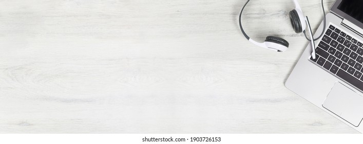 Laptop. Keyboard And Headphones On Grey Desk And Plain Wooden Background Wide Banner. Helpdesk Or Call Center Headset. Distant Learning Or Working From Home, Online Courses Or Support Center Concept.