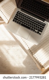 Laptop Keyboard And Wicker Bench On Wooden Floor. Flat Lay, Top View Home Office Workspace. Warm Sunlight Shadows.