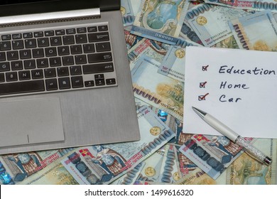 A laptop and a list to do with marked education, home and car on Armenian Dram in AMD 100,000 banknotes. Earned money by working from laptop at home. Freelance work making money concept