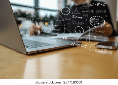 Laptop with mathematical formulas and geometric shapes overlaid in focus, with blurred background showing person holding notebook. Scene represents education, learning, or science.