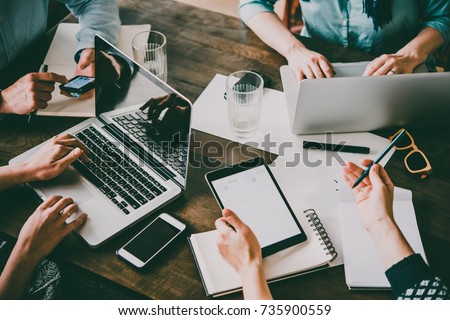 Laptop, mobile phone, tablet and documents on a working table in creative office. Successful teamwork and business startup concept. Toned image