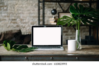 Laptop Mock Up On Wooden Table With Cup Of Coffee Or Tea, Monstera Plant In Vase. Working Space In Loft. Interior Photo