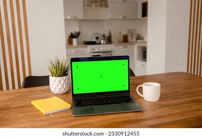 A laptop with a mockup of a green screen stands on the table - Powered by Shutterstock