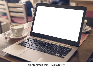 Laptop Mockup On Coffee Shop Desk. Cup Of Coffee Beside. White Screen For Web Page Design Presentation