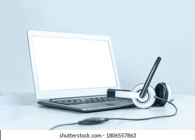Laptop. Mockup screen and headphones on white desk blue background banner. Distant learning or working from home, online courses or shopping minimal concept. Helpdesk or call center headset