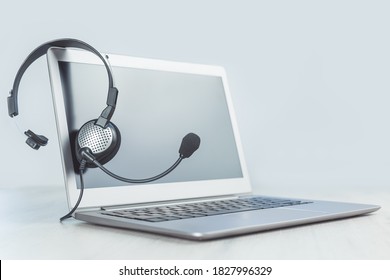 Laptop. Mockup screen and headphones on grey desk and plain background banner. Distant learning or working from home, online courses or support minimal concept. Helpdesk or call center headset