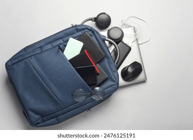 Laptop with Modern gadgets and accessories for work and study in Backpack on white background.