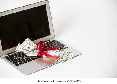 Laptop and money with red ribbon