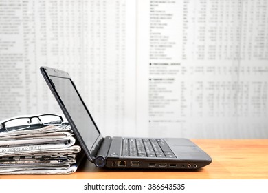 Laptop, Newspaper, Glasses On Wood Board With Blurred Newspaper Background