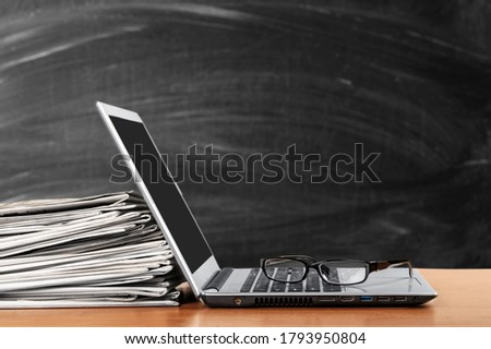 Laptop and newspapers stack on a table with a background
