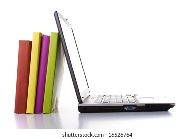 A Laptop Next To A Stack Of Colorful Books