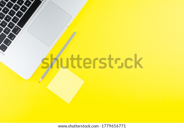 Laptop,  note sticks and pencil\
on yellow background. Flat lay. Copy space. Workplace in the\
office. 
