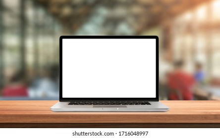 Laptop or notebook with blank screen on wood table in blurry background with coffee shop and nature green bokeh and sun light in morning.