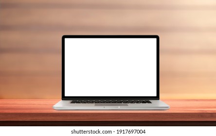 Laptop or notebook with blank screen on wood table in blurry background with wood wall, nature orange bokeh and sunlight in morning.