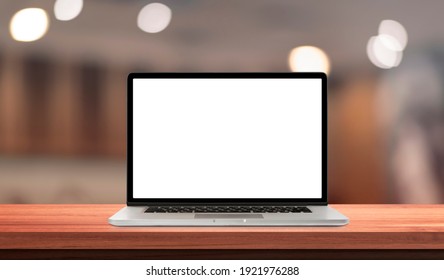Laptop or notebook with blank screen on wood table in blurry background with offee shop or restaurant ,nature orange bokeh and sunlight in morning.