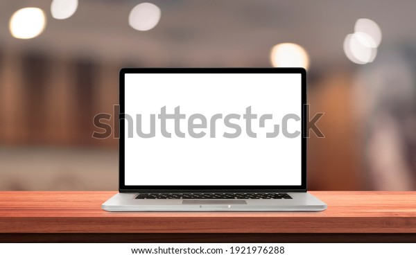 Laptop or notebook with blank screen on wood\
table in blurry background with offee shop or restaurant ,nature\
orange bokeh and sunlight in\
morning.