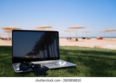 Laptop On Background Tropical Beach. Working Remotely, Summer Vacation Concept, Working On The Beach, Freelance Work And Holiday