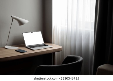 the laptop is on the desktop on a gray background in the hotel. Nearby is a chair, a place to insert in the screen
