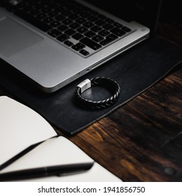 Laptop On A Leather Desk Mat, Leather Bracelet And Notebook On Wooden Table