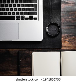 Laptop On Leather Desk Mat, Leather Bracelet, Notebook And Pen On Wood