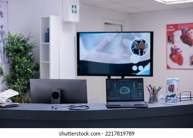 Laptop On Medical Clinic Front Desk Showing Brain Scans. Counter With Medical Articles, Information Leaflets And Electronic Devices In Empty Reception Area With No Users. X Ray Images On Computer