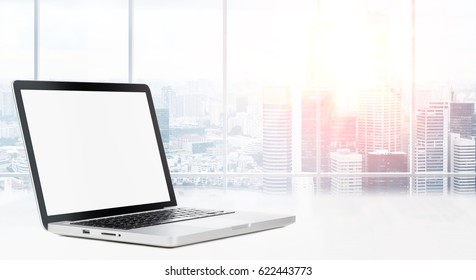 Laptop on table in office with panoramic view of modern downtown skyscrapers at business district - Powered by Shutterstock