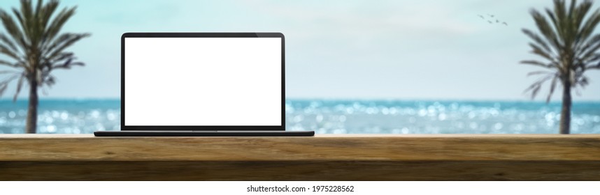 laptop on a table on a sunny day in the summer with beach in the background - Powered by Shutterstock