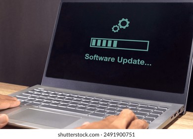 A laptop on the table with updating progress bar on screen. Software system update process concept. 