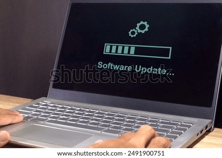 A laptop on the table with updating progress bar on screen. Software system update process concept. 