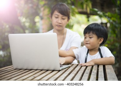 Laptop On The Wooden Table With Blur Of Son Asking Some Question To His Mom While His Mom Working.Vintage Style