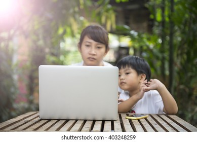 Laptop On The Wooden Table With Blur Of Son Asking Some Question To His Mom While His Mom Working.Vintage Style