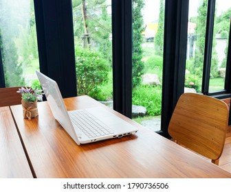 A Laptop On The Wooden Table In The Living Room Near To The Garden.