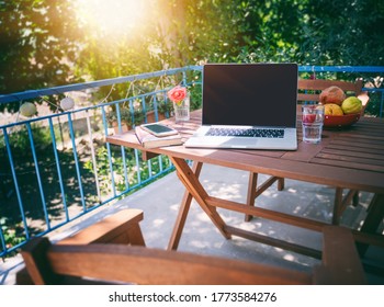 Laptop on a wooden table on a sunny summer terrace, summer mood and vacation in a country house - Powered by Shutterstock