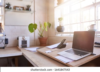 Laptop And Other Business Supplies Sitting On A Table In The Office Area Of A Framing Shop, With Sun Flare Behind