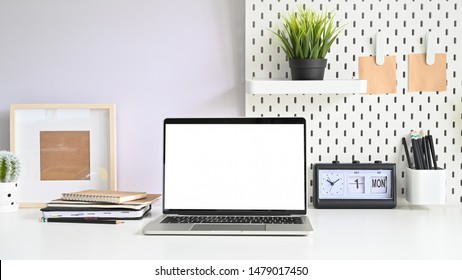 Laptop, Pegboard And Office Supplies On Workspace Table With Empty Monitor Computer.