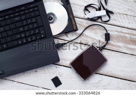 Laptop with pendrive, sd card, CD and portable hard drive. Concept of data storage.