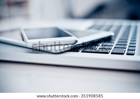 Laptop with phone and tablet pc on white table