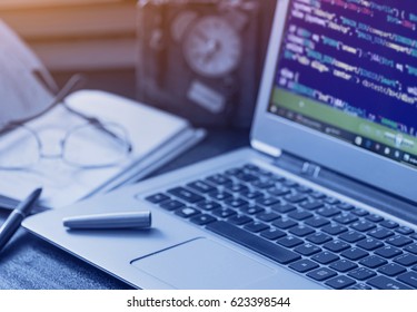 Laptop with programming code on the table. Tinted image. Low depth of field. 