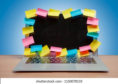 Laptop In Reminders With Colored Stickers Notes On The Display Frame On Table With Blue Wall. Many Unfulfilled Tasks, Deadline