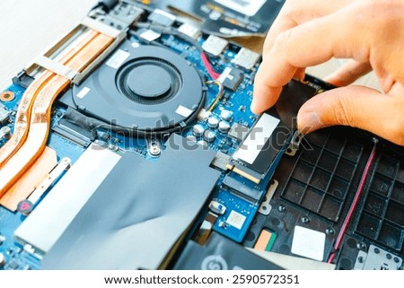 Laptop repair engineer PC computer and motherboard install random access memory ram ssd in computer lab top. The master installs the disk in his hands.
