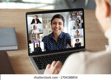 Laptop Screen Over Woman Shoulder View, Indian Businesswoman Leading Videoconference Distant Communication Group Videocall Conversation. Diverse Friends Using Modern Tech Enjoy Virtual Meeting Concept