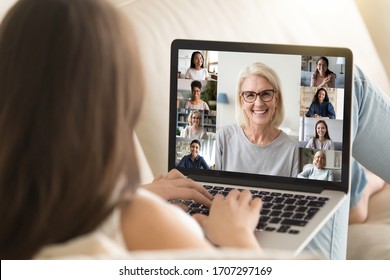 Laptop Screen View Mature 50s Lady Lead Group Videocall Distant Talk With Different Ethnicity Age Women. View Over Girl Shoulder Sit On Sofa Involved At Remote Chat, Empowerment Movement Club Concept