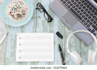 laptop, sheet music paper note notebook and laptop, headphones and donuts  on blue rustic wood background - Powered by Shutterstock