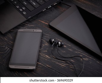 Laptop, smart phone, tablet pc and headset on wooden background