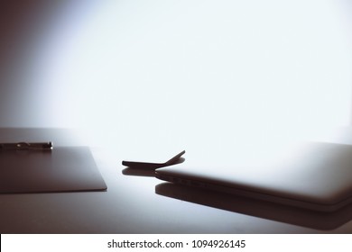 Laptop with stack of folders on table on white background
