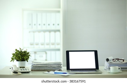 Laptop with stack of folders on table on white background