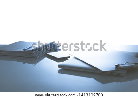 Laptop with stack of folders on table on white background