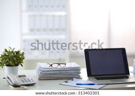 Laptop with stack of folders on table on white background