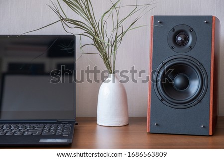 A laptop standing on a table with a speaker system
